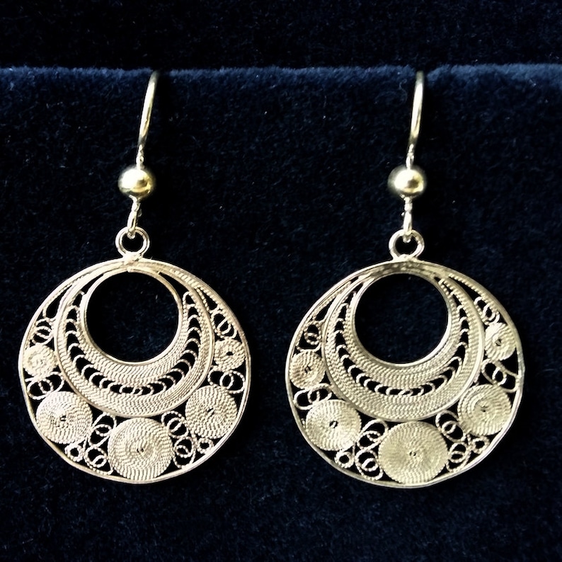 Puede incluir: Un par de pendientes de filigrana de plata con un dise&ntilde;o circular. Los pendientes tienen un patr&oacute;n delicado e intrincado y son perfectos para agregar un toque de elegancia a cualquier atuendo.