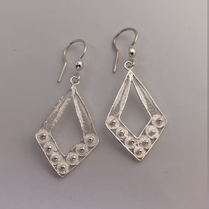 Puede incluir: Un par de pendientes de filigrana de plata con forma de diamante y pequeños acentos redondos.