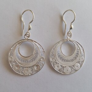 Puede incluir: Un par de pendientes de filigrana de plata con un dise&ntilde;o circular. Los pendientes tienen un patr&oacute;n delicado e intrincado y un cierre simple de gancho.