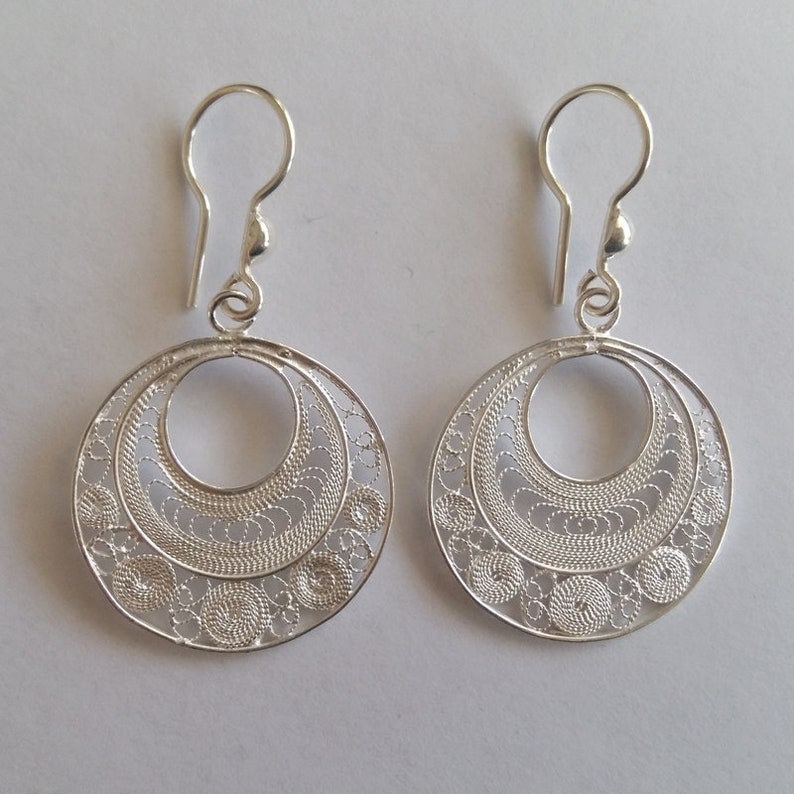 Puede incluir: Un par de pendientes de filigrana de plata con un dise&ntilde;o circular. Los pendientes tienen un patr&oacute;n delicado e intrincado y un cierre simple de gancho.