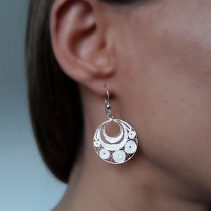 Puede incluir: Pendientes de filigrana de plata con un dise&ntilde;o circular. Los pendientes son delicados e intrincados, con un patr&oacute;n de peque&ntilde;os c&iacute;rculos y curvas.