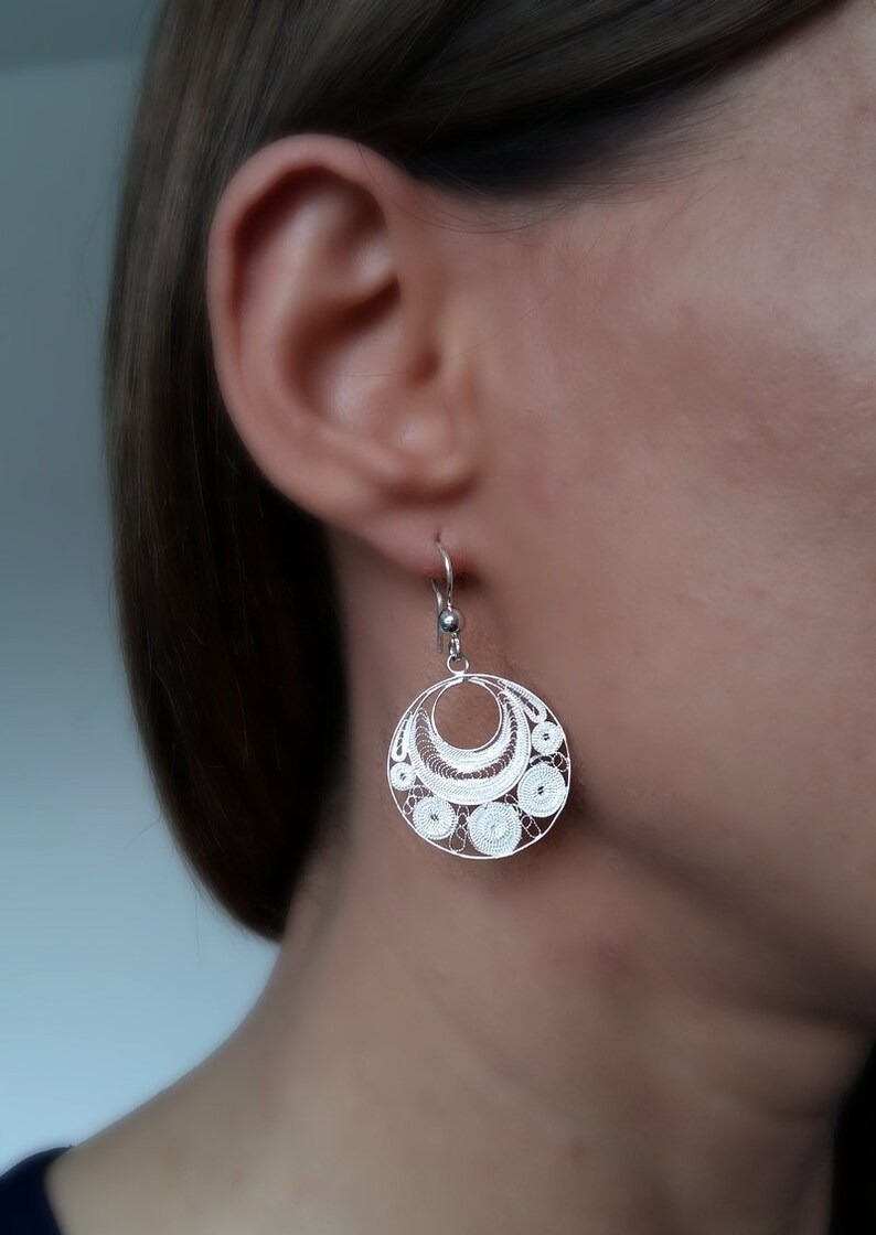 Puede incluir: Pendientes de filigrana de plata con un dise&ntilde;o circular. Los pendientes son delicados e intrincados, con un patr&oacute;n de peque&ntilde;os c&iacute;rculos y curvas.