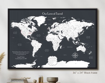 May include: A black framed world map with white countries and red push pins. The map is titled "Our Love of Travel" and has a key for the push pins. The text below the map reads "Liam & Faith Traveling Together since 2007". The map is 36 inches by 24 inches.