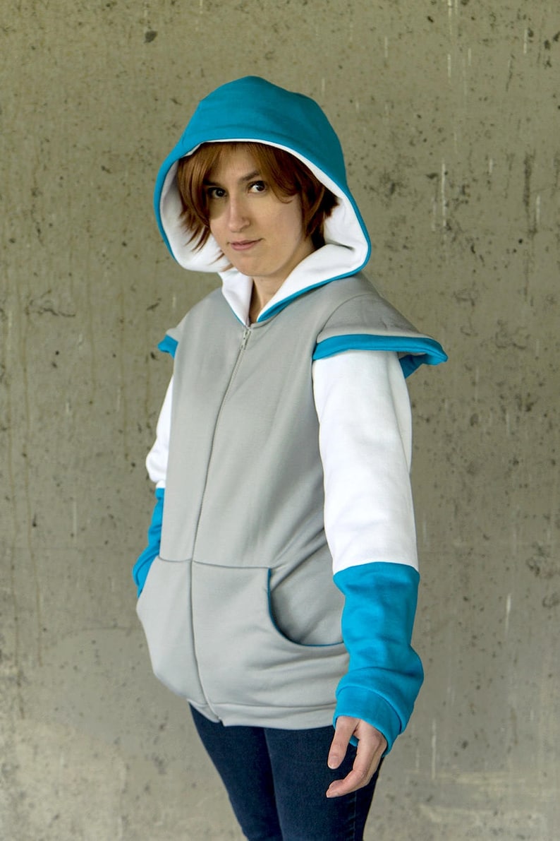 May include: A gray hooded sweatshirt with white sleeves and blue accents. The hood is lined with white and has a blue trim. The sweatshirt has a zipper closure and two pockets.