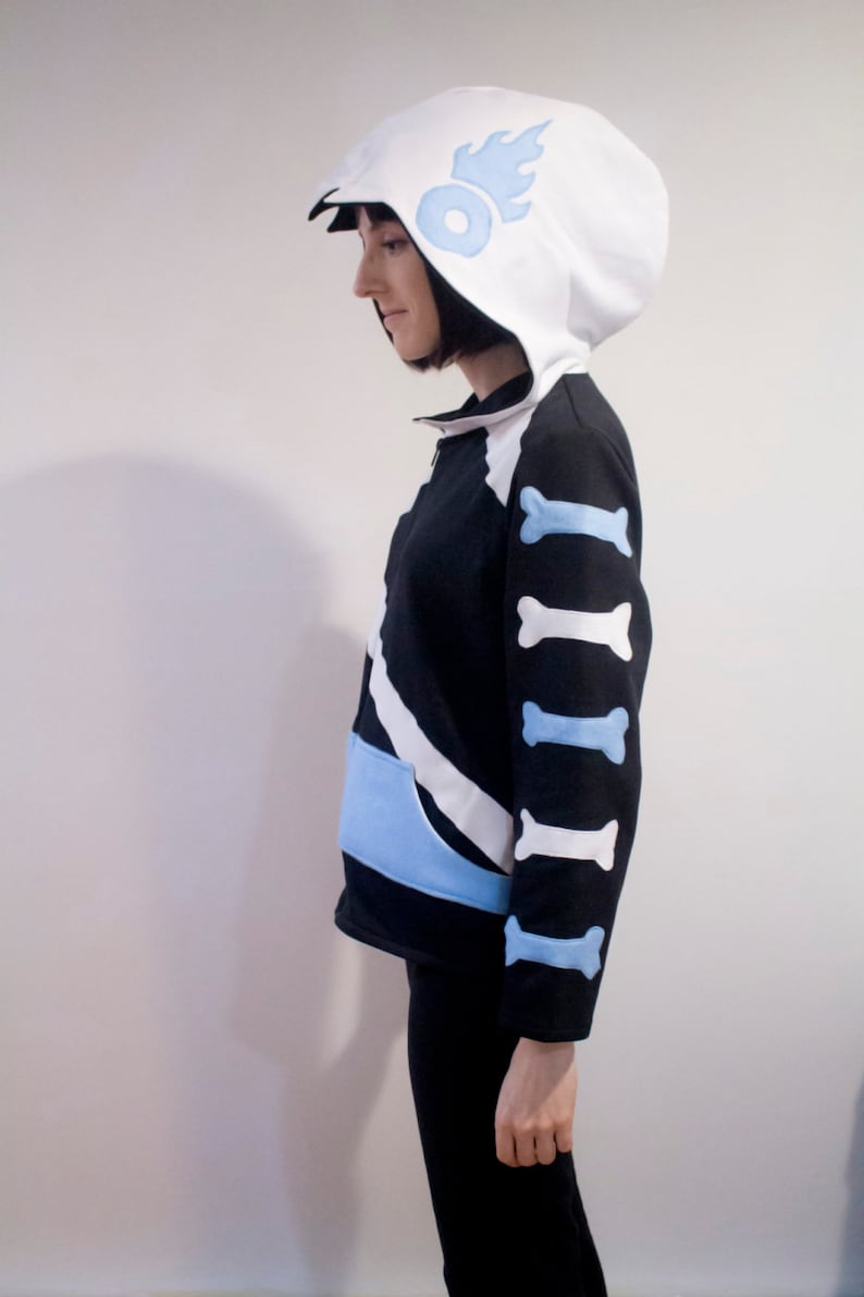 May include: A black and white hoodie with a blue and white bone pattern on the sleeves. The hoodie has a white hood with a blue flame design.