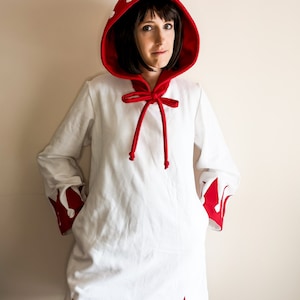 May include: A white hooded robe with red trim and a red bow tie. The hood has white flames on it. The robe has red trim on the sleeves and bottom.