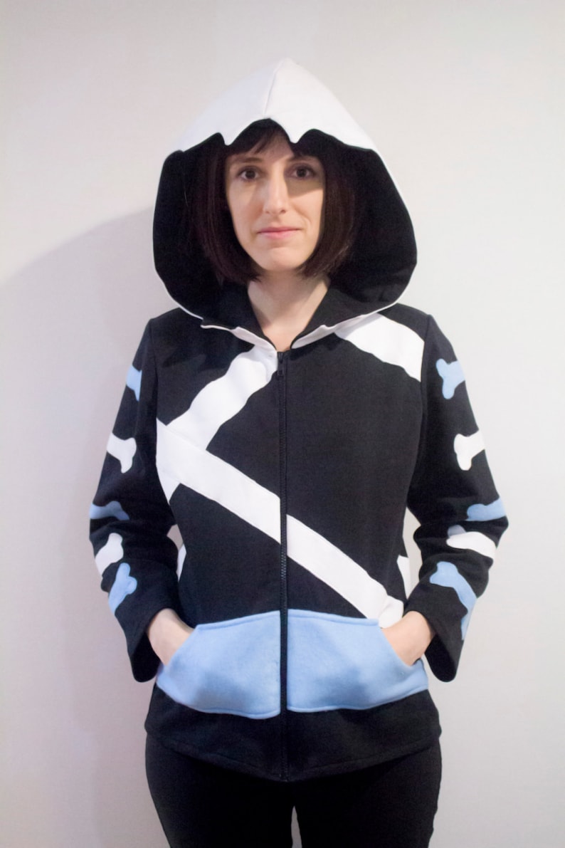 May include: A black and white hooded sweatshirt with a blue pocket and white bone-shaped designs on the sleeves.