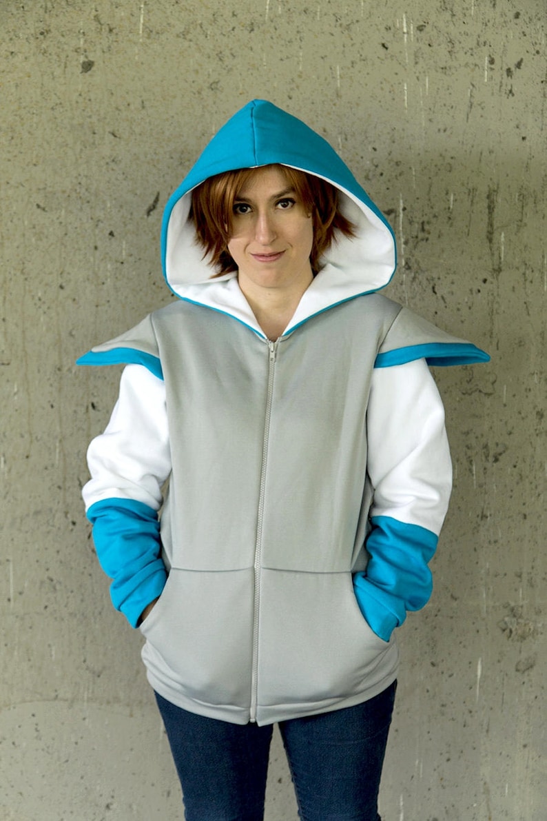 May include: A gray zippered hoodie with white and blue accents. The hood is lined with white and has a blue exterior. The sleeves are white with blue cuffs. The person is wearing blue jeans.