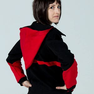 Puede incluir: Una sudadera con capucha negra y roja con una capucha roja contrastante y mangas negras. La sudadera tiene una franja roja en el pecho.