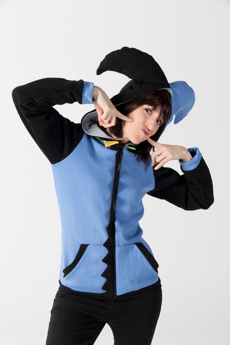 May include: A blue and black zip-up hoodie with a pointed hood and a jagged design along the zipper and pockets. The hoodie has black sleeves and a light blue body. The hood is black with a blue accent.