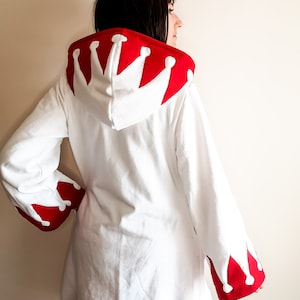 May include: White hooded sweatshirt with a red crown design on the hood and red trim on the sleeves and hem.