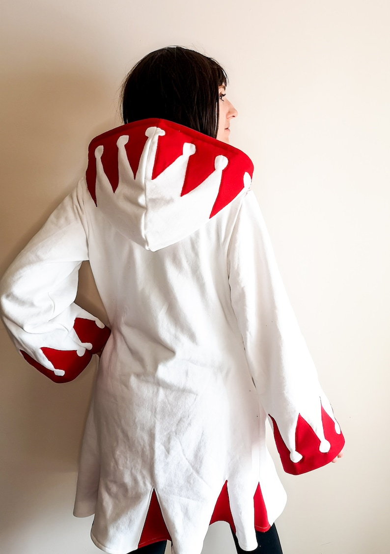May include: White hooded sweatshirt with a red crown design on the hood and red trim on the sleeves and hem.