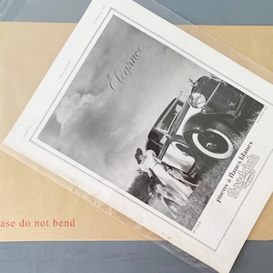 Puede incluir: Anuncio vintage en blanco y negro para neum&aacute;ticos Goodrich con un coche y dos mujeres con vestidos de pie en un campo. El texto dice "Elegancia" y "neum&aacute;ticos de flancos blancos Goodrich", con el logotipo de Goodrich debajo.