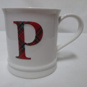 Può includere: Tazza in ceramica bianca con una lettera "P" a quadri rossi e verdi sul davanti.