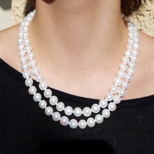 Puede incluir: Un collar de perlas blancas de doble cadena. Las perlas son redondas y lisas.