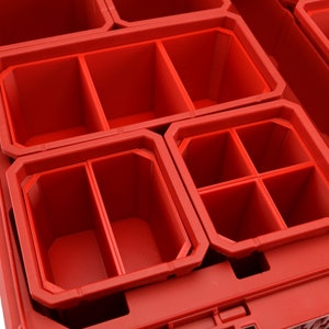 以下が含まれることがあります： 仕切り付きの赤いプラスチック製の収納コンパートメント。コンパートメントは互いにネストされています。