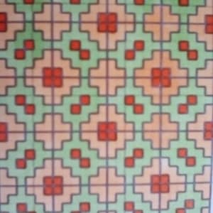 May include: A repeating geometric pattern featuring squares, crosses, and diamond shapes. The design incorporates a palette of orange, green, and red, with dark gray outlines. The pattern is symmetrical and covers the entire surface.