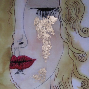 May include: A close-up of a woman's face with gold leaf accents on her cheek. Her eye is closed and her lips are painted a deep red. Her hair is drawn in brown lines and is styled in a loose wave.