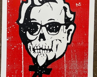 May include: A red and white print featuring a skull wearing sunglasses and a black bow tie. The image has a distressed, textured appearance with the text "PRINT MARIA" at the bottom.