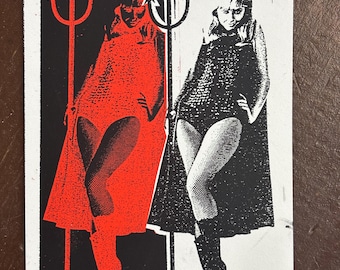 May include: A rectangular print featuring a split-color design. The left side is black with a red figure holding a trident, while the right side is white with a black figure holding a trident. Both figures wear capes and boots.