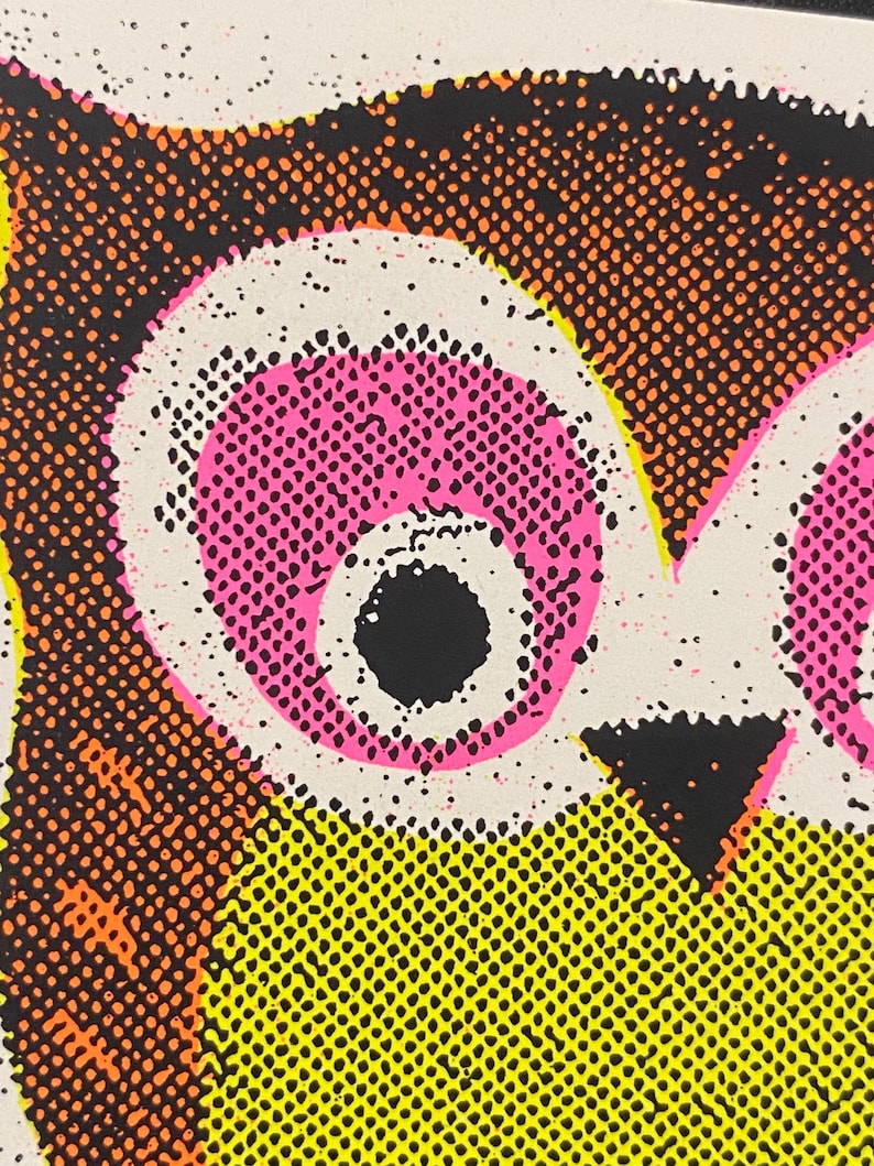 May include: Close-up of a pop art style illustration featuring a stylized owl. The owl's eyes are pink with black pupils, set against a white background. The owl's body is yellow with orange and black details.