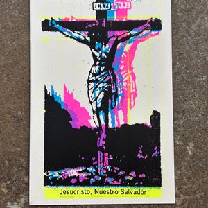 May include: A rectangular print featuring a black silhouette of Jesus Christ on the cross, layered with vibrant cyan and magenta offset printing effects. The bottom of the print displays the text Jesucristo, Nuestro Salvador in black font.