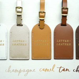 May include: Five leather luggage tags in different colors: white, champagne, camel, tan, and chocolate. Each tag has the text "LETTER + LEATHER" embossed in gold.