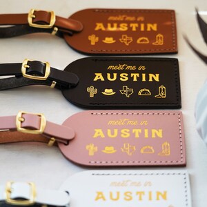 K&ouml;nnte beinhalten: Vier Leder-Gep&auml;ckanh&auml;nger mit goldener Beschriftung und Symbolen. Die Anh&auml;nger zeigen den Text "meet me in AUSTIN" und ein Kaktus, einen Cowboyhut, die Umrisse des Bundesstaates Texas, ein Taco und einen Cowboystiefel. Die Anh&auml;nger sind braun, schwarz, rosa und wei&szlig;.