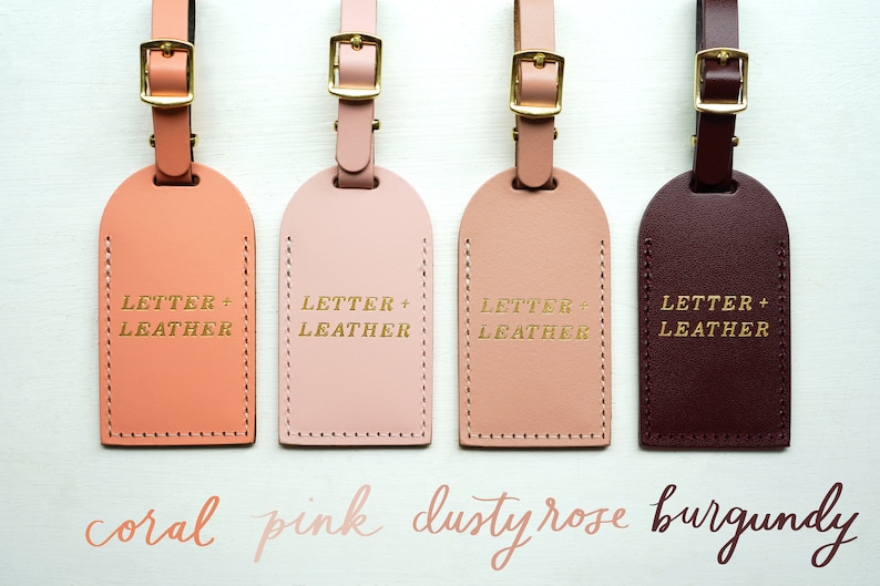 May include: Four leather luggage tags in coral, pink, dusty rose, and burgundy colors. Each tag has gold lettering that reads "LETTER + LEATHER".