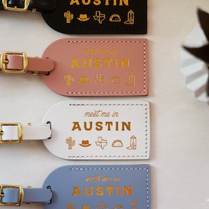 K&ouml;nnte beinhalten: Vier Leder-Gep&auml;ckanh&auml;nger mit goldener Beschriftung "meet me in AUSTIN" und einem Kaktus, einem Cowboyhut, einem Texas-Stern, einem Taco und einem Cowboystiefel. Die Anh&auml;nger sind in Schwarz, Rosa, Wei&szlig; und Blau.