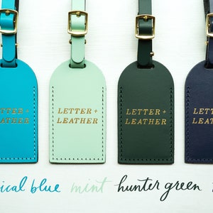 May include: Four leather luggage tags in different colors: tropical blue, mint, hunter green, and navy. Each tag has the text "LETTER + LEATHER" embossed in gold.