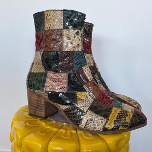 May include: A pair of brown, green, and yellow patchwork ankle boots with a block heel. The boots are made of snakeskin and have a pointed toe.