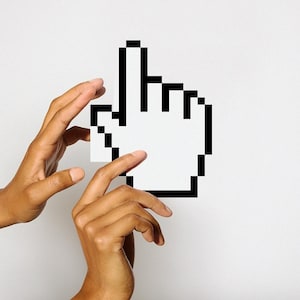 May include: Two hands holding a white pixelated cursor, resembling a computer mouse pointer.