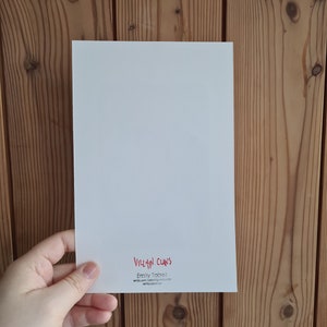 May include: White card with red text that reads "VILLAIN CLANS" and "Emily Tabat" with an email address and website address.