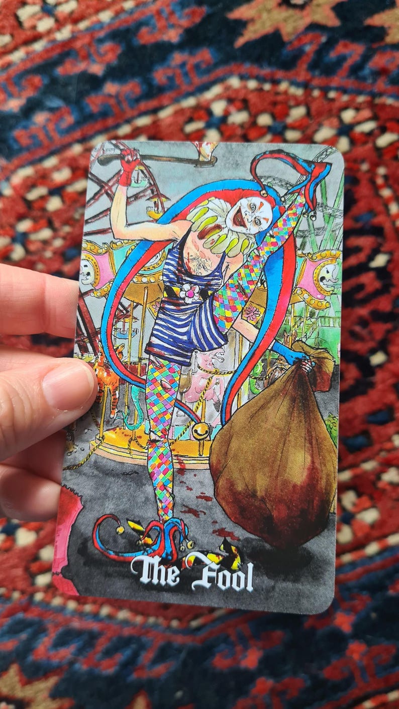 May include: Tarot card illustration of "The Fool" featuring a jester-like figure in colorful attire, including a striped top and patterned leggings. The background depicts a carousel scene with a brown sack. The card's title is at the bottom.