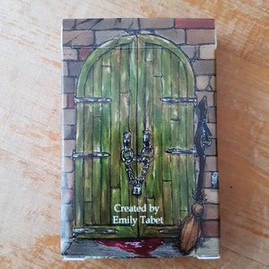 May include: A green wooden door with a chain and lock, a brick wall, and a broom leaning against the door. The text "Created by Emily Tabet" is printed below the door.