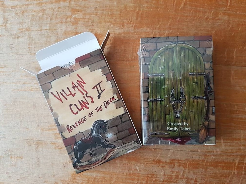 May include: A box for a deck of playing cards called "Villain Clans II: Revenge of the Deck". The box is red, white, and black with a brick pattern and a rocking horse illustration. The text "Created by Emily Tabet" is on the front of the box.