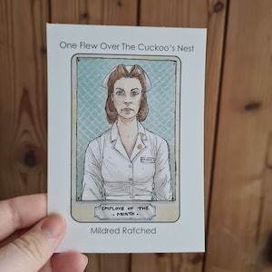 Puede incluir: Una ilustración de estilo vintage de una mujer con un uniforme de enfermera blanco con una etiqueta de nombre que dice "Ratched". La ilustración está enmarcada con un borde marrón claro y tiene un fondo amarillo con el texto "One Flew Over The Cuckoo's Nest" en la parte superior y "Employee of the Month" debajo de la imagen. El texto "Mildred Ratched" está en la parte inferior de la ilustración.