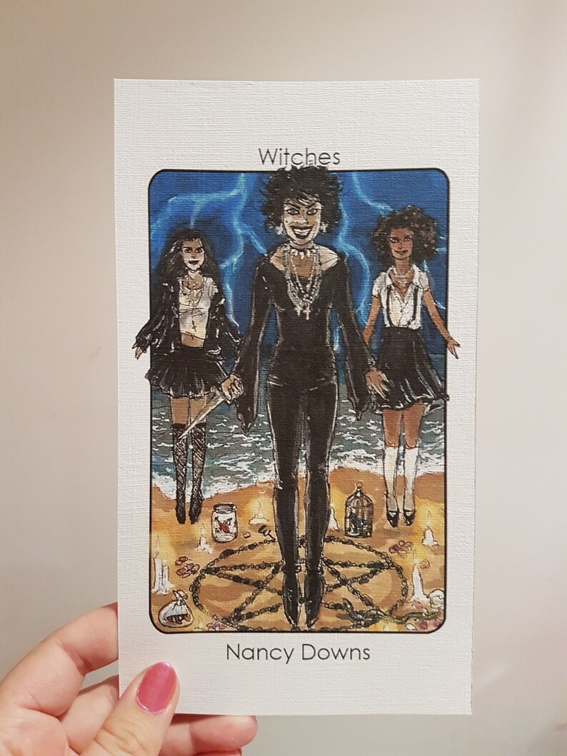 May include: A tarot card illustration depicting three women dressed in black, standing in a circle with candles and a pentagram. The card is titled "Witches" and signed "Nancy Downs".