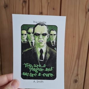 Puede incluir: Una tarjeta ilustrada verde y negra con una cita de la película Matrix. La cita dice "Eres una plaga y nosotros somos la cura." La tarjeta presenta un dibujo del Agente Smith de la película Matrix. La tarjeta está titulada "The Matrix" y firmada "A. Smith".