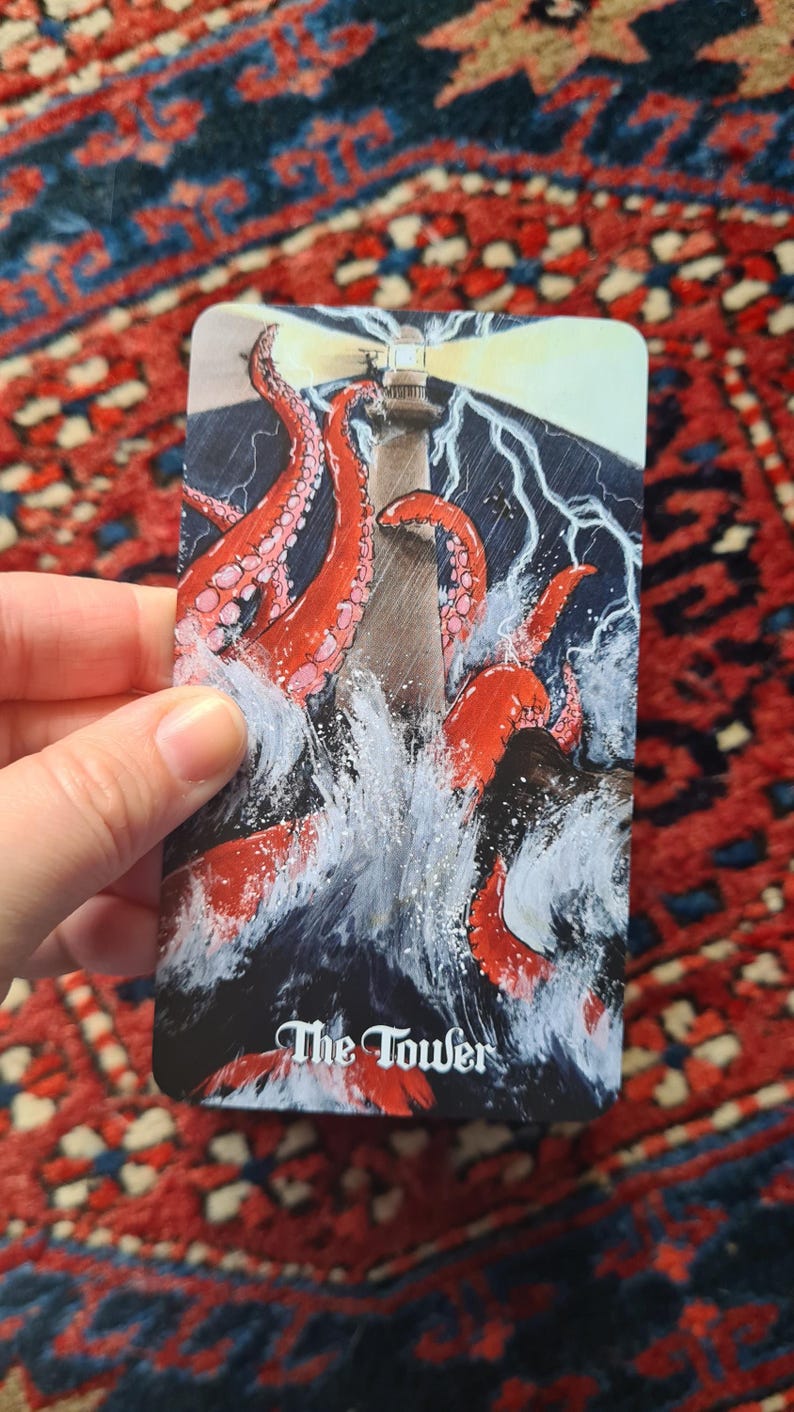 May include: A tarot card depicting a lighthouse being attacked by a giant octopus in a stormy sea. The card is labeled "The Tower" in white script. The image is set against a red and blue patterned background.