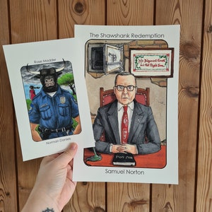 May include: Two illustrated cards featuring characters from the film "The Shawshank Redemption". The first card features a black and white illustration of a police officer with a bull's head. The second card features a colour illustration of Samuel Norton, a character from the film, sitting at a desk with a bible. The text on the card reads "The Shawshank Redemption" and "Samuel Norton".