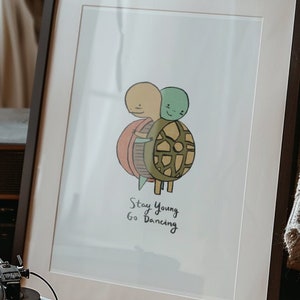 May include: A framed print with a cartoon illustration of two turtles, one green and one orange, with the text "Stay Young Go Dancing".