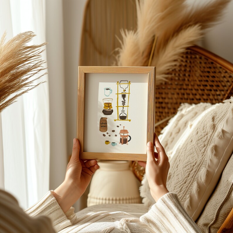 May include: A framed illustration of different coffee brewing methods, including a pour-over coffee maker, a French press, and a coffee grinder. The illustration is in a light brown frame and features a light blue background with brown, yellow, and white accents.