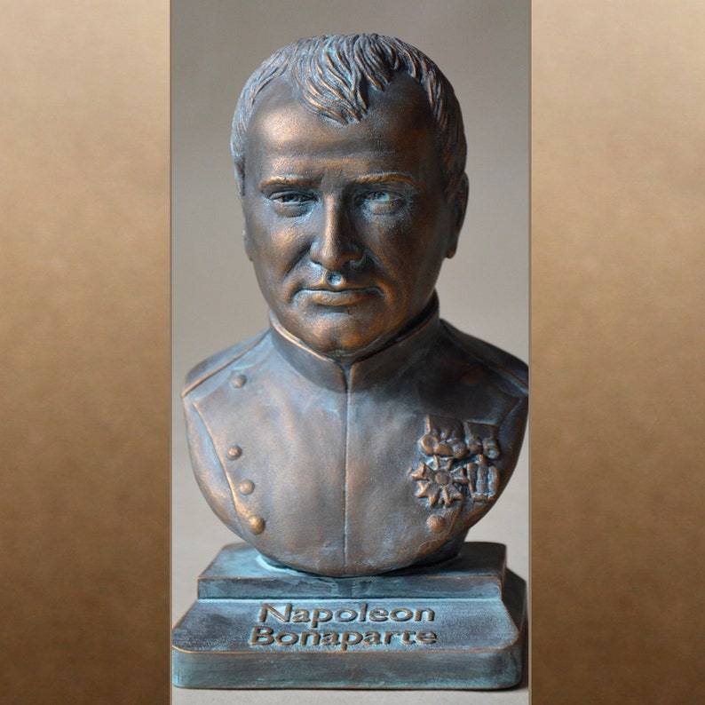 May include: A bronze bust of Napoleon Bonaparte on a green base. The bust is detailed with a military uniform and a star-shaped emblem. The base is inscribed with "Napoleon Bonaparte".