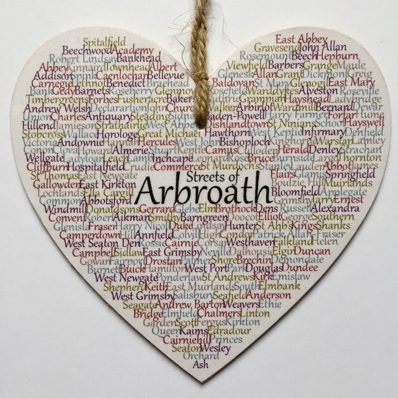 May include: A wooden heart-shaped ornament with the words "Streets of Arbroath" in a large font. The heart is decorated with a variety of smaller words, including street names and place names, in a variety of colours.