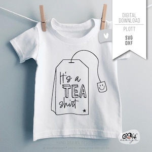 Puede incluir: Una camiseta blanca con una ilustración en blanco y negro de una bolsita de té con el texto "It's a TEA shirt" en ella.
