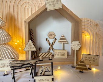 May include: Wooden toy signs with German text, including "Lier zeht bald ein Wichtel ein" (Elf is coming soon), "Stop", and "Lier wird gewervelt" (Elf is being worked on). There is also a wooden toolbox with the word "Werkzeug" (tools) on it.
