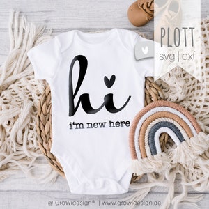 Könnte beinhalten: Ein weißer kurzärmeliger Babybody mit dem schwarzen Schriftzug "hi", einem kleinen Herz über dem "i" und dem darunter gedruckten Text "i'm new here". Das Kleidungsstück ist zusammen mit einem kleinen dekorativen Regenbogen und Babyschuhen abgebildet.