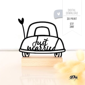 Op de afbeelding: Een zwart-witte 3D-geprinte auto-vormige huwelijksdecoratie met de tekst "Just Married" op de achterkant. De auto heeft een hartvormige vlag en is gemonteerd op een houten voet. De woorden "Digital Download" en "3D Print" zijn ook zichtbaar.